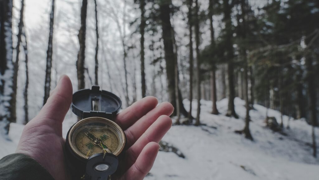 A hand holding a compass in a snowy forest, Liezen, Austria.